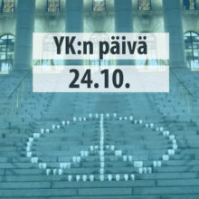 Teksti: YK:n päivä 24.10. Taustalla kuva rauhanmerkistä eduskuntatalon portailla